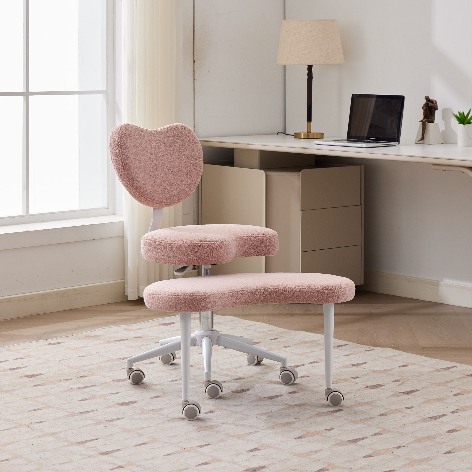 Pink plush cross-legged meditation chair with wheels and lumbar support in a bright home office.