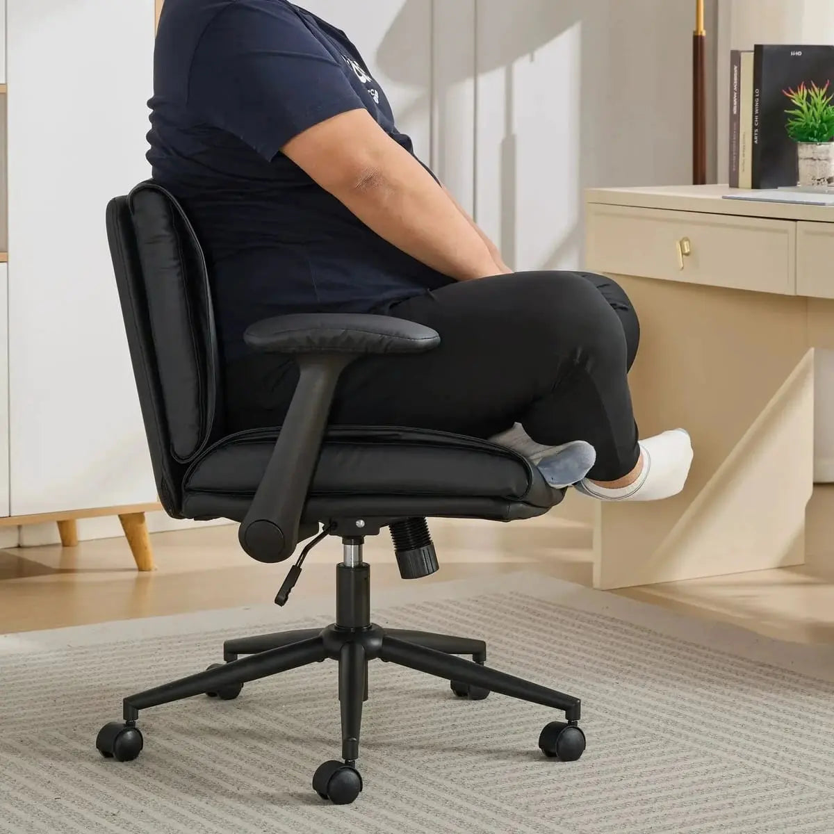 Black Doba ergonomic leather cross-legged chair with adjustable flip-up armrests and black metal frame.