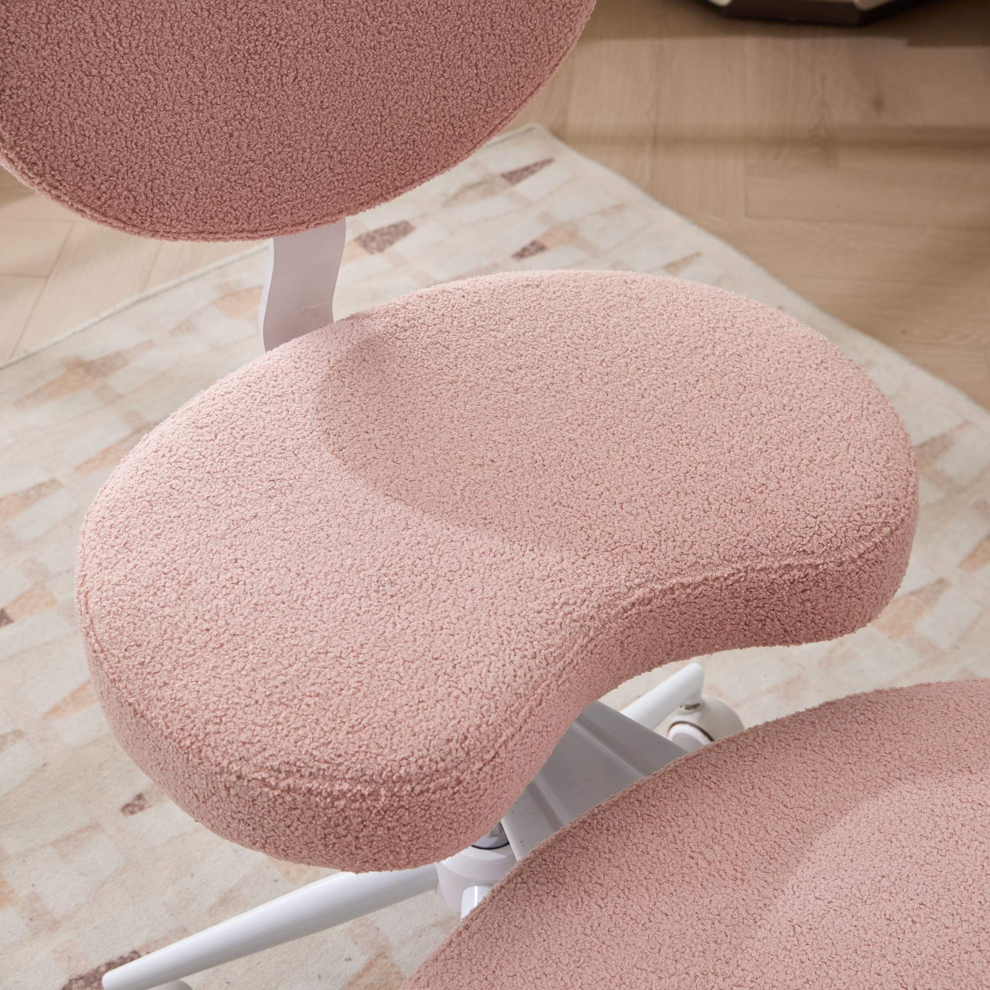 Pink plush meditation cross-leg chair with lumbar support and wheels on a white frame.